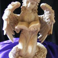 ivory kneeling angel reading a book