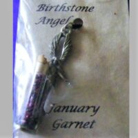 glass vial of garnets the birthstone for January with pewter angel