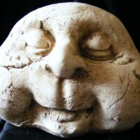 stone man garden ornament with close eyes