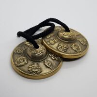 gold coloured tingsha with decorative tops and symbols inside 4 top view