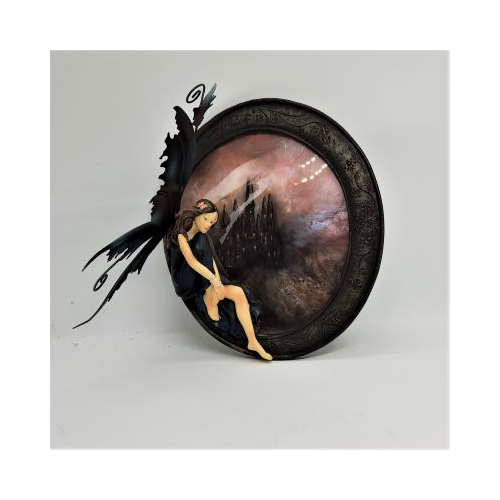 resin fairy seated on picture frame with picture of castle behind showing removable metals wings