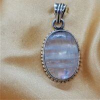 oval rainbow moonstone set in silver with scalloped edges