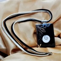 rectangular black shell with swirl insert and silver decoration over one corner on double thong