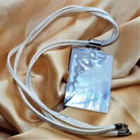 rectangular shell with silver decoration over one corner on double thong